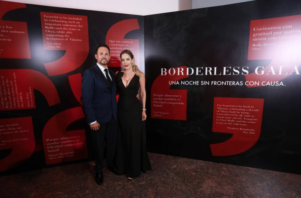El empresario Marco Antonio Moreno Gómez Santelices posando junto a una acompañante en la Borderless Gala, frente a un muro con frases de agradecimiento y el título del evento 'Una noche sin fronteras con causa'.