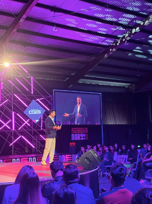 Marco Santelices habla sobre el escenario frente a una pantalla gigante que proyecta su imagen en vivo, con el público de fondo en el evento Innova Norte 2026.